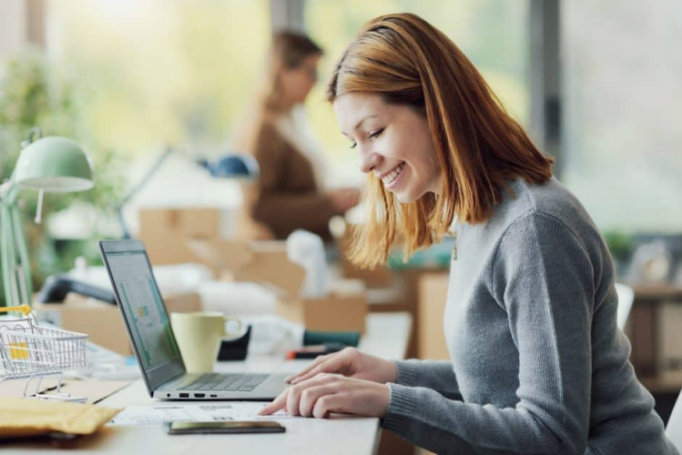 E-commerce employee sitting at the desk and working with a laptop